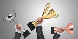 Hands holding up trophies — an allusion to the Caring Stars awards.